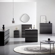 Moderne schwarze Kommoden und Sideboards in einem minimalistischen Raum, frontal und seitlich betrachtet, mit dekorativen Elementen und einem runden Teppich.