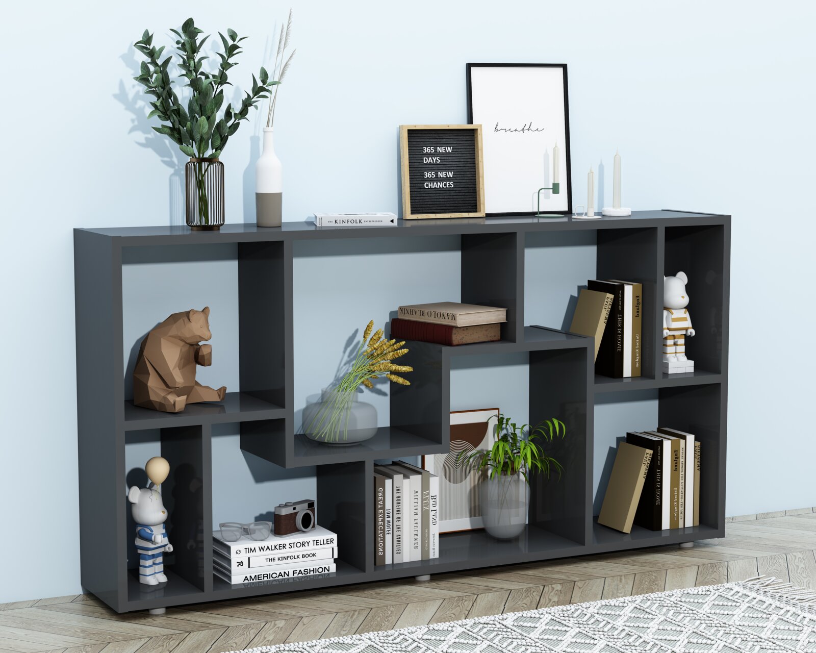 Modernes, anthrazitfarbenes Regal mit versetzten Fächern, dekoriert mit Büchern, Pflanzen, Vasen und Figuren, in Frontansicht leicht von rechts vor heller Wand und Holzboden.
