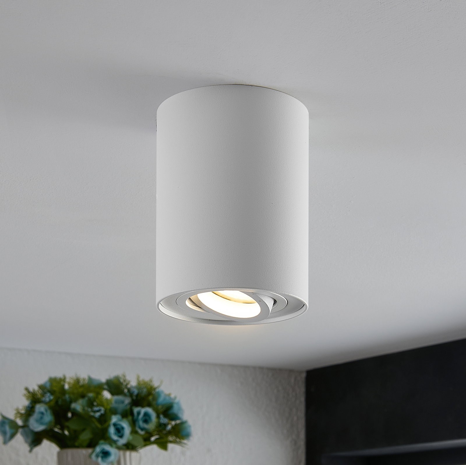 Zylindrischer Deckenstrahler in Weiß, von unten fotografiert, mit warmem Lichtschein.