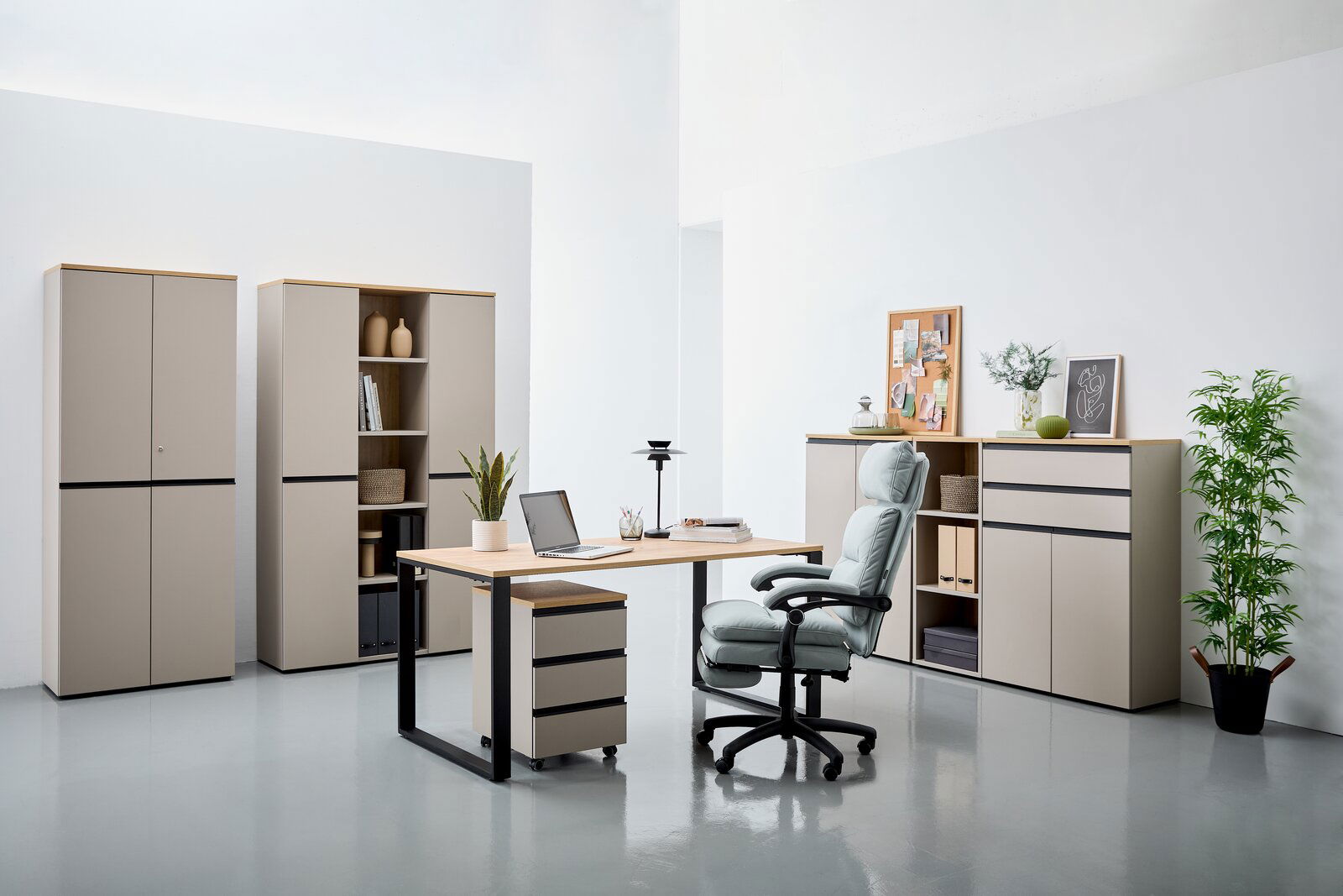 Moderne Büromöbel in einem hellen Raum, bestehend aus einem Schreibtisch mit Rollcontainer, einem ergonomischen Bürostuhl und mehreren Aktenschränken. Perspektive von vorne.