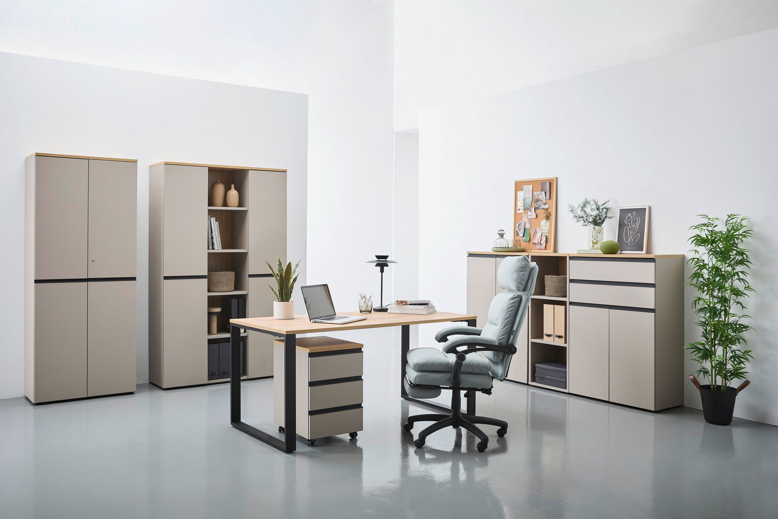 Moderne Büromöbel in einem hellen Raum, bestehend aus einem Schreibtisch mit Rollcontainer, einem ergonomischen Bürostuhl und mehreren Aktenschränken. Perspektive von vorne.