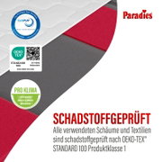 Nahaufnahme einer Paradies-Matratze in schräger Schnittperspektive mit sichtbaren roten und grauen Schaumschichten sowie CertiPUR-, OEKO-TEX Standard 100- und Pro-Klima-Zertifizierung für schadstoffgeprüfte Materialien.