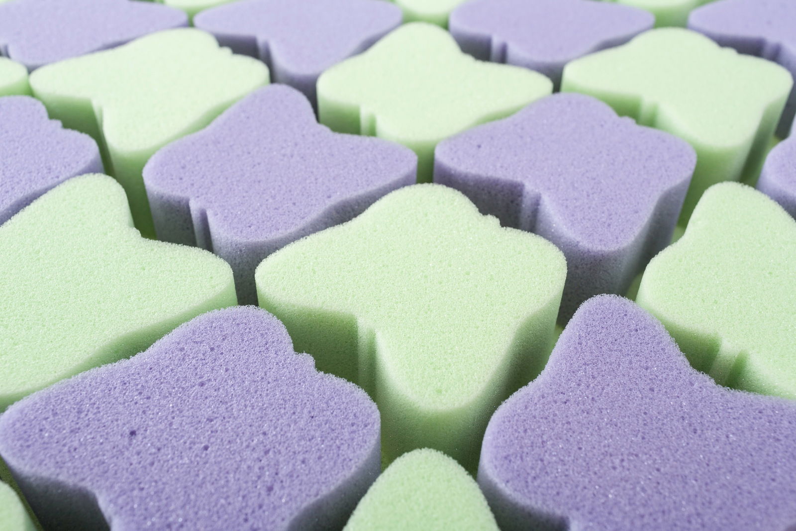 Nahaufnahme von Schaumstoffelementen in Schmetterlingsform in Grün und Lila, perspektivisch von oben betrachtet.