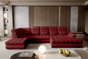 Frontale, leicht erhöhte Perspektive auf ein modernes, bordeauxrotes U-förmiges Wohnlandschaft-Sofa mit gesteppten Sitzflächen in einem stilvollen Wohnzimmer mit Holz- und Steinwand.