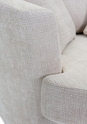 Nahaufnahme eines Sessels mit hellbeigem, strukturiertem Stoffbezug, Blick auf die Armlehne und Sitzfläche.