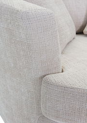 Nahaufnahme eines Sessels mit hellbeigem, strukturiertem Stoffbezug, Blick auf die Armlehne und Sitzfläche.