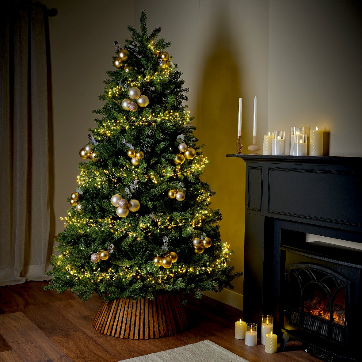 Ein festlich geschmückter Weihnachtsbaum mit goldenen Kugeln und warmweißen Micro-LED-Lichtern, seitliche Perspektive.