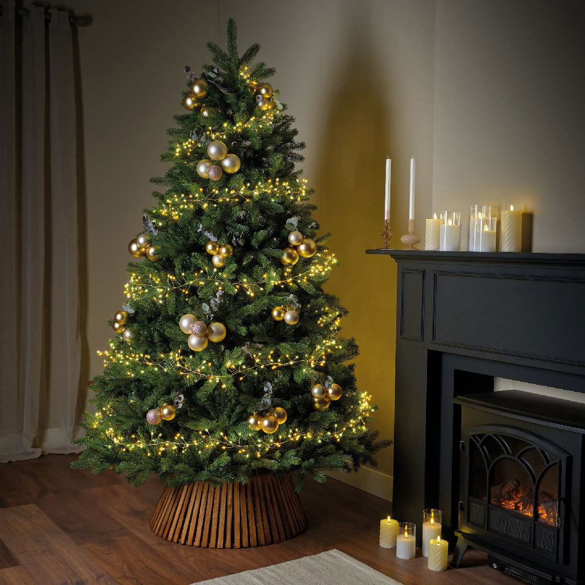 Ein festlich geschmückter Weihnachtsbaum mit goldenen Kugeln und warmweißen Micro-LED-Lichtern, seitliche Perspektive.