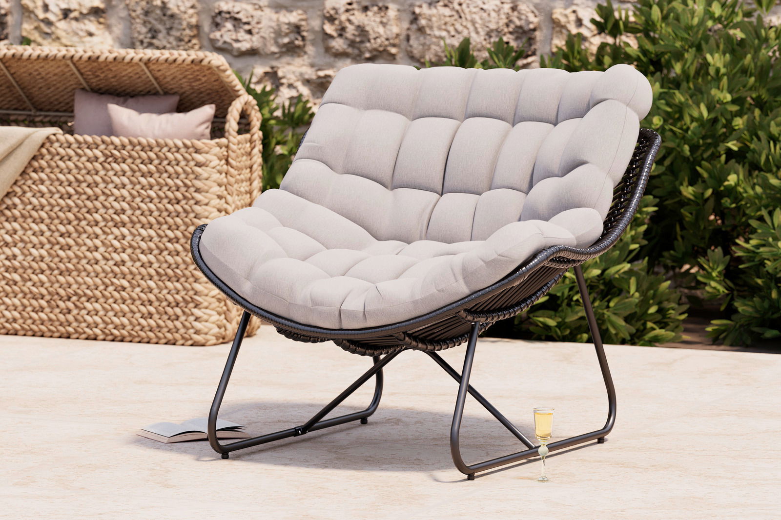 Bequemer Relaxsessel mit gepolstertem, hellgrauem Kissen und schwarzem Metallrahmen, seitliche Perspektive, im Freien aufgestellt.