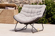 Bequemer Relaxsessel mit gepolstertem, hellgrauem Kissen und schwarzem Metallrahmen, seitliche Perspektive, im Freien aufgestellt.