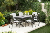 Gartenmöbel-Set mit sechs grauen Stapelstühlen und einem Tisch auf einer Terrasse, umgeben von üppigem Grün, aus der Perspektive von schräg vorne.
