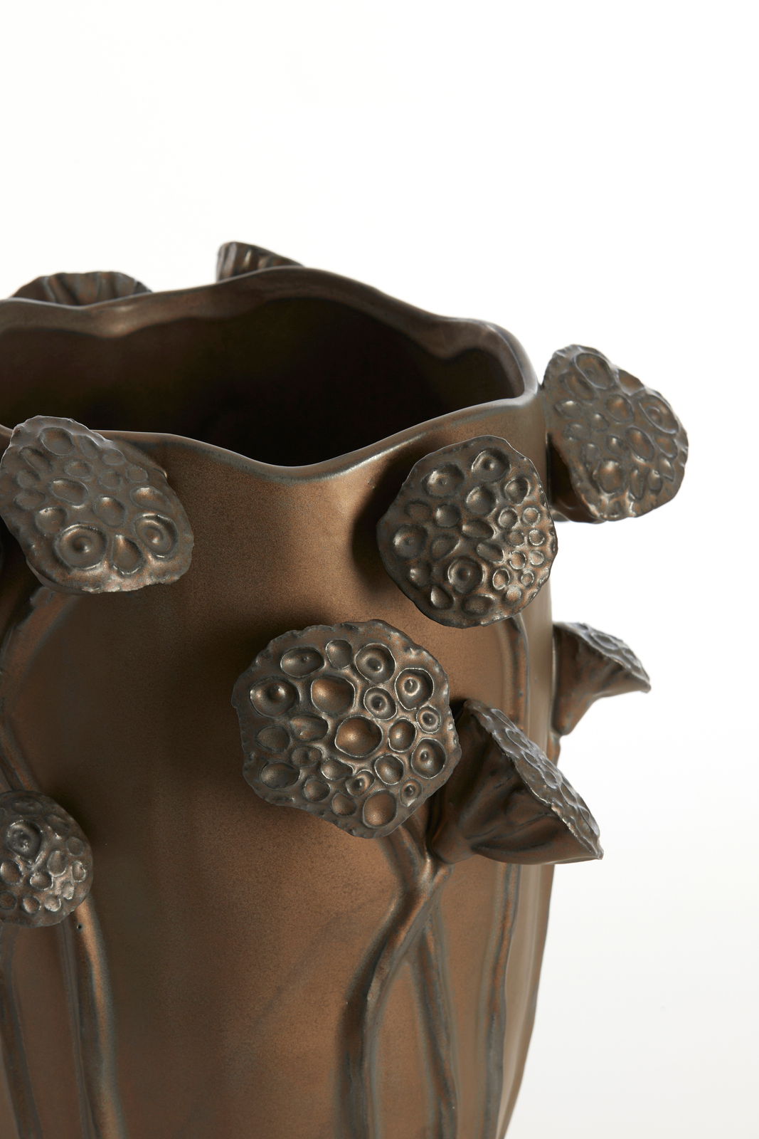Nahaufnahme einer bronzefarbenen Vase mit erhabenen, blütenartigen Verzierungen. Die Perspektive zeigt die obere Hälfte der Vase.