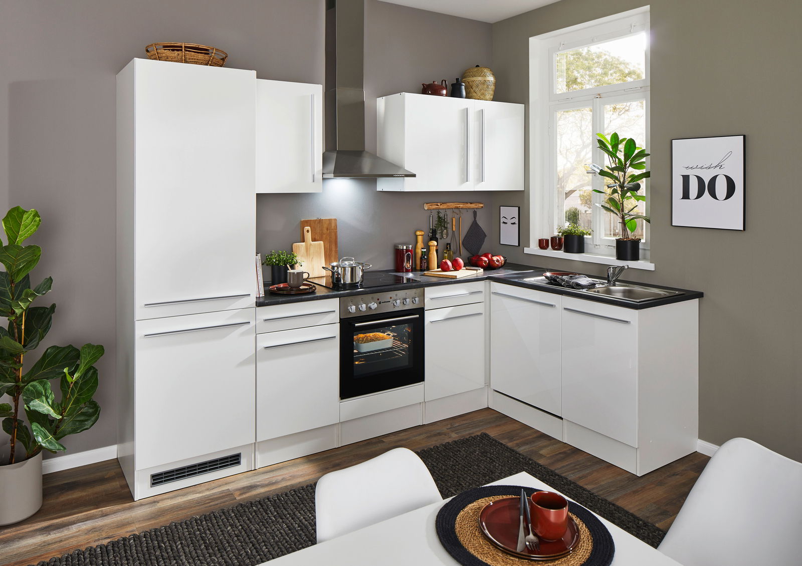 Moderne weiße Küche mit Eckunterschrank, Blick von vorne. Die Küche ist mit einem Herd, einer Spüle und dekorativen Elementen ausgestattet.