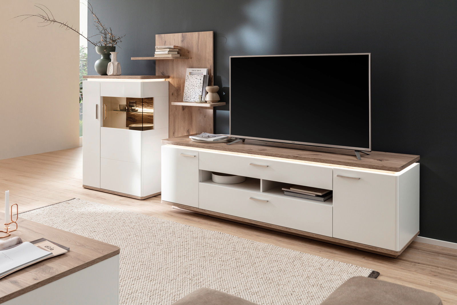 Moderne Wandkombination in hellem Holz und Weiß mit TV-Schrank und Vitrine, seitliche Perspektive