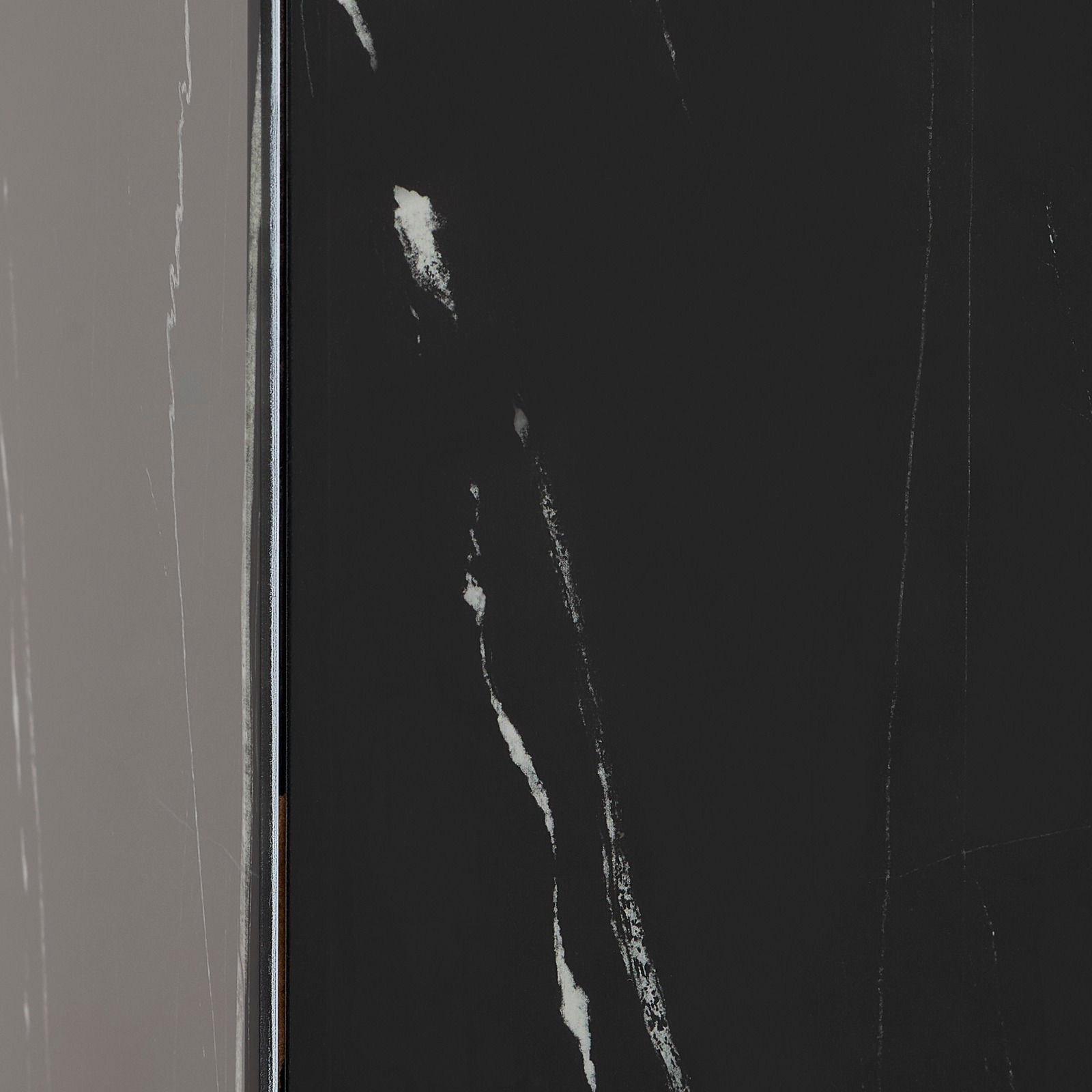 Nahaufnahme eines Beistelltisches mit schwarzer, marmorierter Oberfläche, seitliche Perspektive