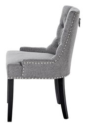 Seitenansicht eines grauen Stuhls mit gepolsterter Rückenlehne und Nietenverzierung, Modell SAVIK.