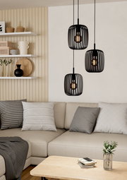 Moderne schwarze Pendelleuchte mit drei Lampenschirmen in einem gemütlichen Wohnzimmer, seitliche Perspektive.