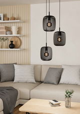 Moderne schwarze Pendelleuchte mit drei Lampenschirmen in einem gemütlichen Wohnzimmer, seitliche Perspektive.