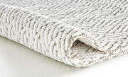 Nahaufnahme eines weißen Badteppichs mit strukturierter Oberfläche, seitliche Perspektive.