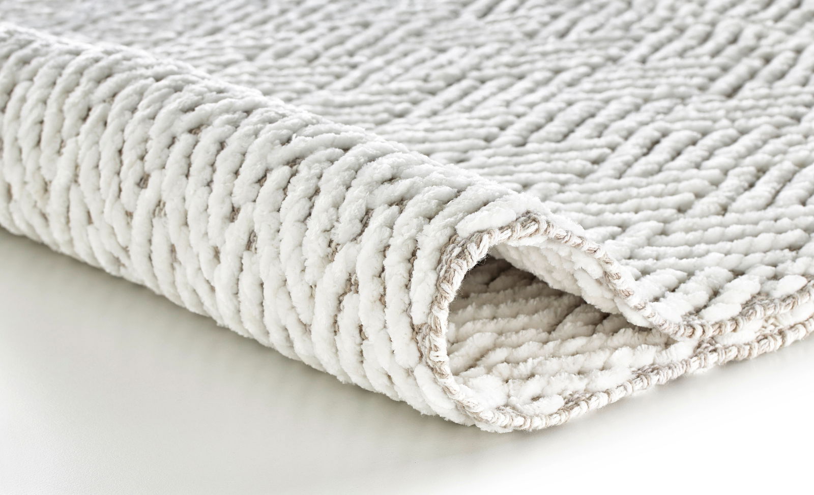 Nahaufnahme eines weißen Badteppichs mit strukturierter Oberfläche, seitliche Perspektive.