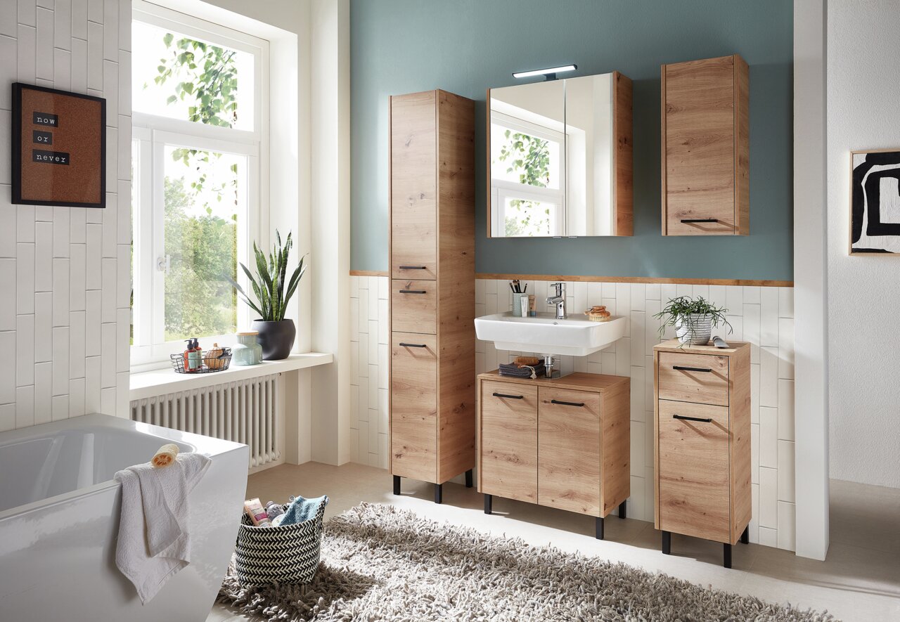 Moderne Badezimmermöbel in Holzoptik, bestehend aus einem hohen Wandschrank, einem Waschbeckenunterschrank und einem Hängeschrank, aus der Perspektive eines hellen, stilvoll eingerichteten Badezimmers.