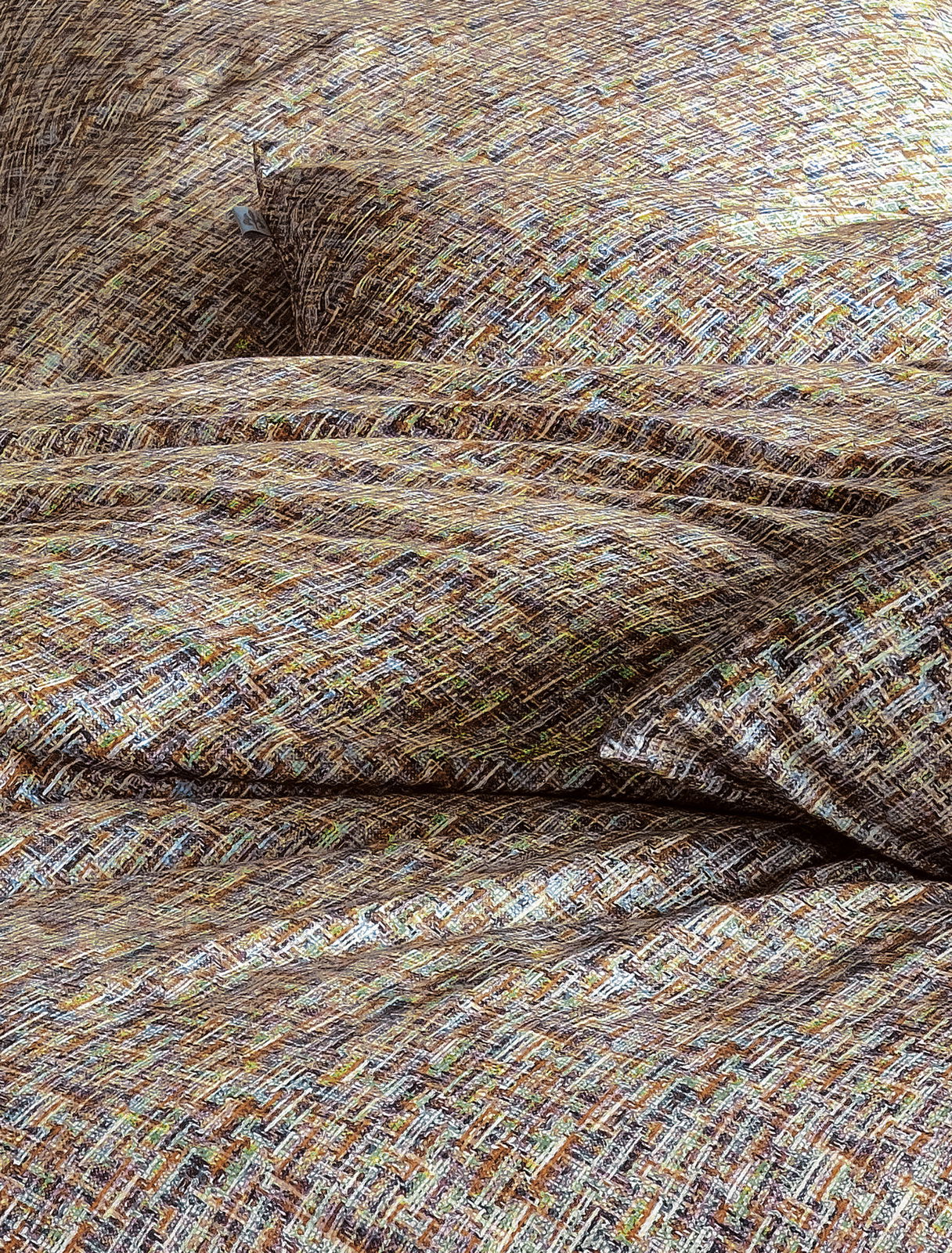 Nahaufnahme von Bettwäsche mit einem bunten, texturierten Muster in Erdtönen.