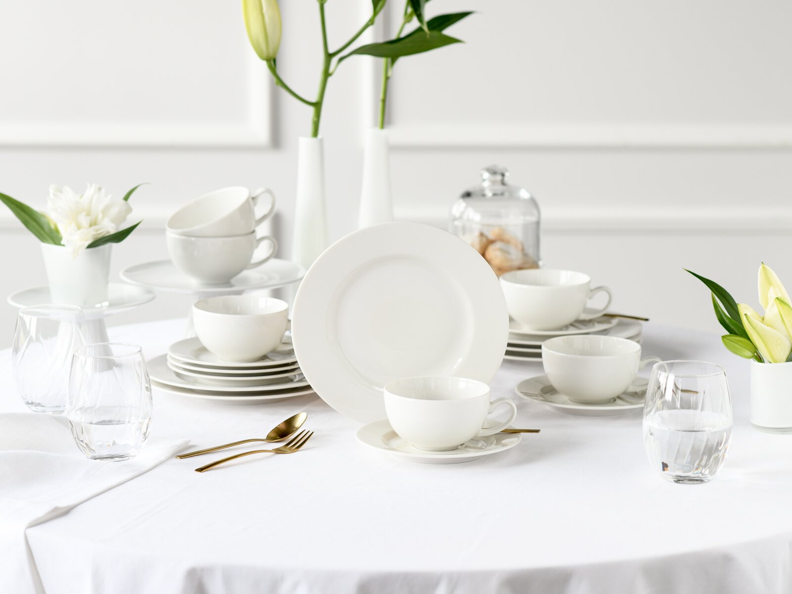 Creatable Teeservice 18-tlg VENICE Weißes Porzellan-Geschirrset mit Tellern, Tassen und Untertassen auf gedecktem Tisch, frontale Perspektive auf den großen Teller im Vordergrund