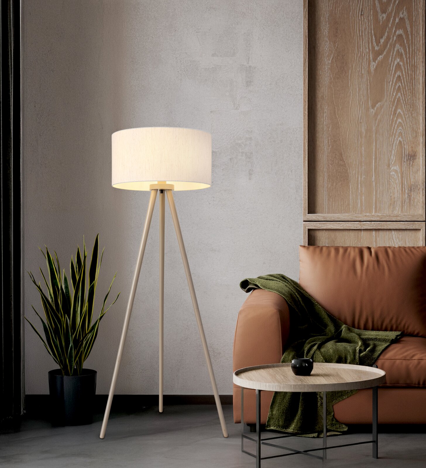 Beige Dreibein-Stehlampe mit zylindrischem Stoffschirm in Wohnzimmerecke neben braunem Sofa und kleinem Beistelltisch, Frontansicht auf Augenhöhe