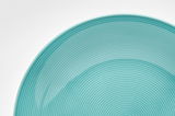 Nahaufnahme eines türkisfarbenen Tellers mit feinen konzentrischen Kreisen, von oben betrachtet.