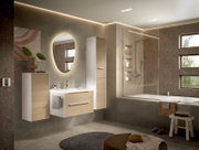 Moderne badkamer met een aan de muur bevestigde wastafel en een hoge kast in wit met houtlook, een ovale verlichte spiegel en een badkuip met glazen douchewand; perspectief: licht schuin breedbeeldperspectief van voren.