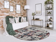 Runder Designer Teppich mit abstraktem Muster in einem modernen Wohnzimmer mit Backsteinwand, Sofa und Regal, aus der Vogelperspektive betrachtet.