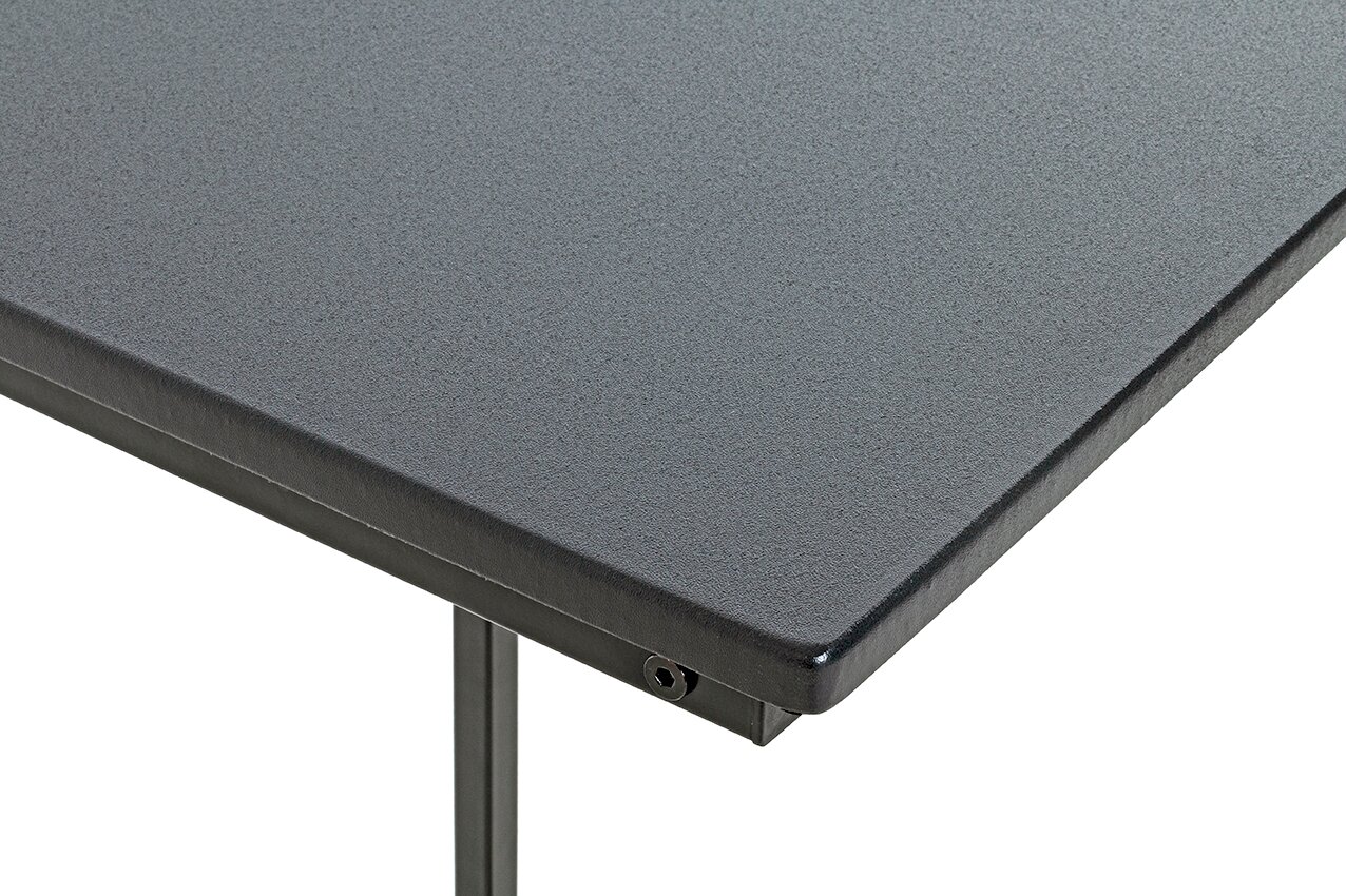 Detailaufnahme einer grauen, strukturierten Tischplatte mit Metallkante und Tischbein, perspektivisch schräg von oben (Ecke im Vordergrund)
