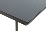 Detailaufnahme einer grauen, strukturierten Tischplatte mit Metallkante und Tischbein, perspektivisch schräg von oben (Ecke im Vordergrund)