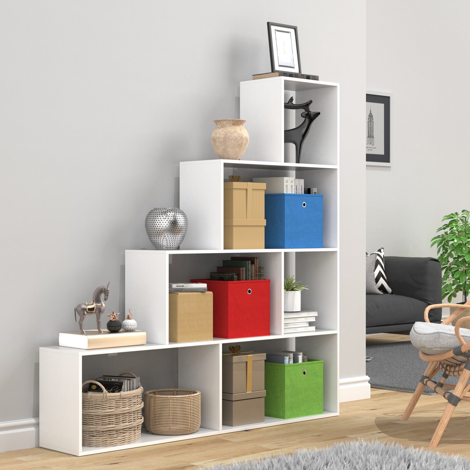Weißes, modular aufgebautes Würfelregal mit offenen Fächern und bunten Aufbewahrungsboxen sowie Dekoobjekten im Wohnzimmer, Ansicht schräg von vorn.