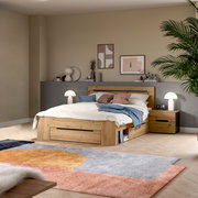Modernes Holzbett mit Stauraum-Schublade und passendem Nachttisch im Schlafzimmer, schräg von vorne aus leicht erhöhter Perspektive fotografiert