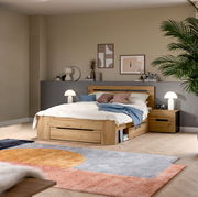 Modernes Holzbett mit Stauraum-Schublade und passendem Nachttisch im Schlafzimmer, schräg von vorne aus leicht erhöhter Perspektive fotografiert