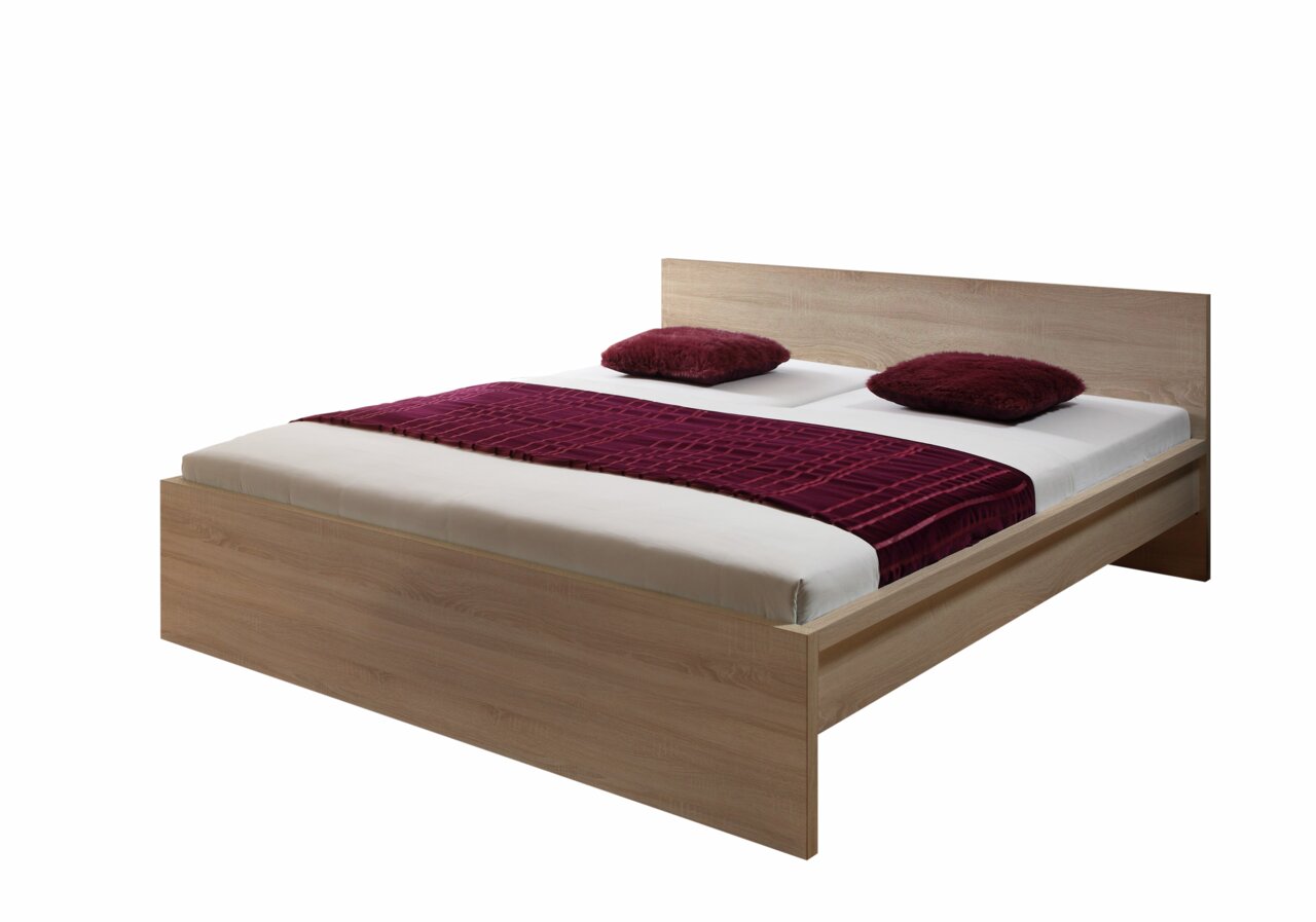 Holzbett mit Kopfteil, zwei roten Kissen und einer roten Decke, seitliche Perspektive