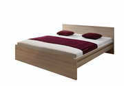 Holzbett mit Kopfteil, zwei roten Kissen und einer roten Decke, seitliche Perspektive