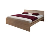 Holzbett mit Kopfteil, zwei roten Kissen und einer roten Decke, seitliche Perspektive