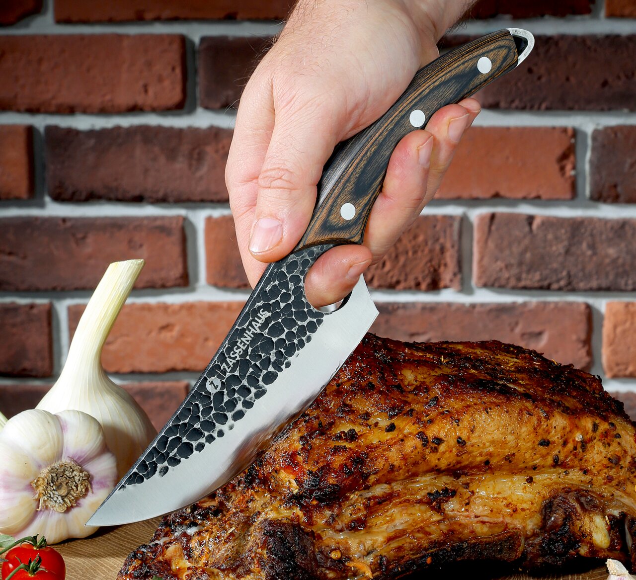 Kochmesser RANGER 15 cm mit gehämmertem Klingenmuster, Holzgriff und einer Hand, die es hält, während es ein gebratenes Stück Fleisch schneidet. Perspektive von der Seite.