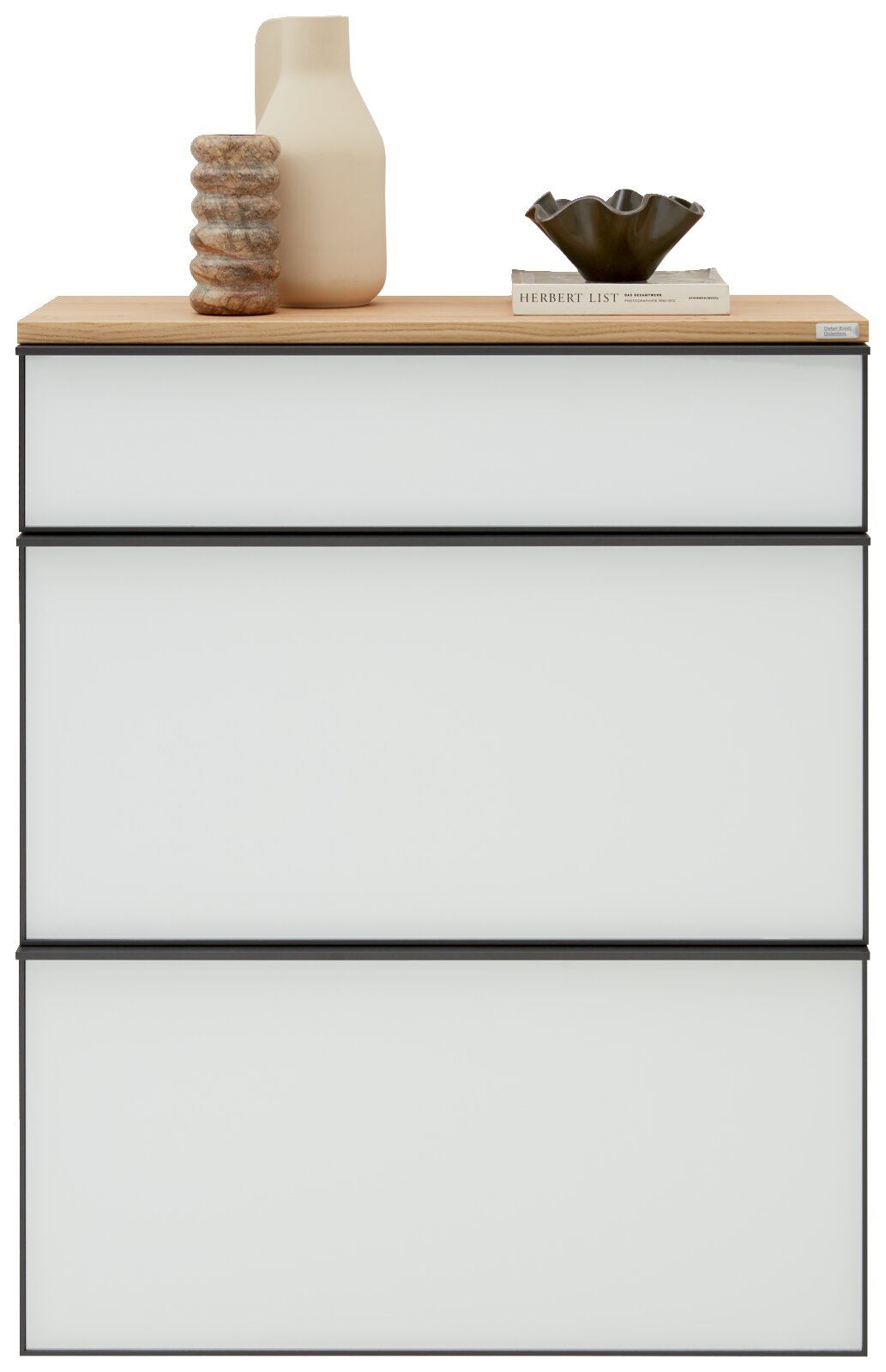 Moderne hangende schoenenkast met drie witte lades en een houten oppervlak, versierd met een vaas, een boek en een schaal, gezien van voren.