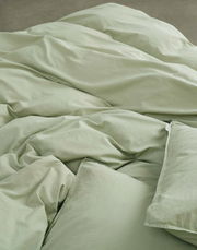 Nahaufnahme von grüner Bettwäsche in 155x220cm Größe, die auf einem Bett liegt.