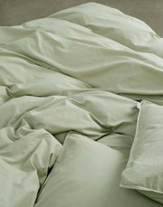 Nahaufnahme von grüner Bettwäsche in 155x220cm Größe, die auf einem Bett liegt.