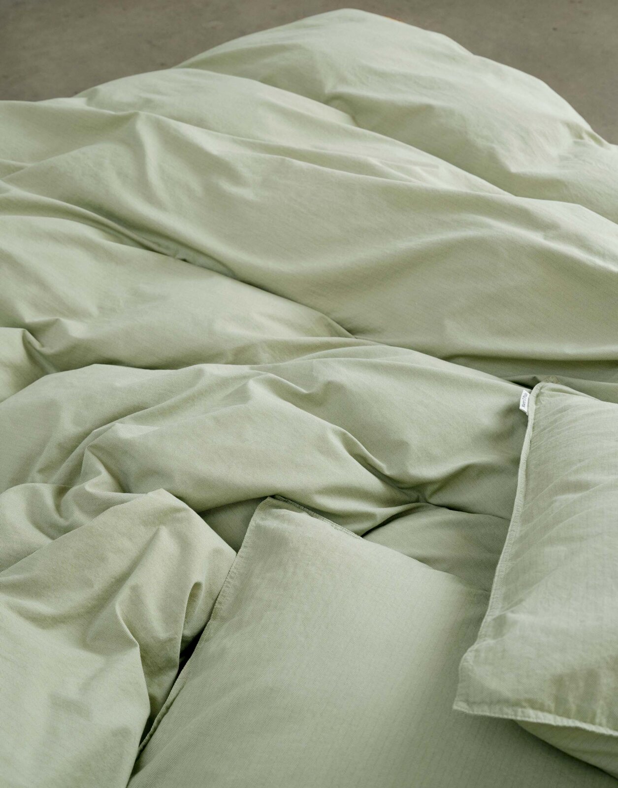 Nahaufnahme von grüner Bettwäsche in 155x220cm Größe, die auf einem Bett liegt.