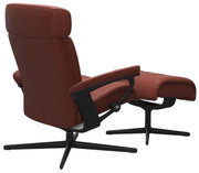 Achterkant van een bruine fauteuil met bijpassende voetenbank, modern ontwerp met zwart metalen frame