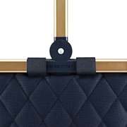 Close-up van een donkerblauw, gewatteerd Carrybag-frame met goudkleurige handvatten, gezien vanaf de voorkant.