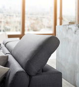 Graues Sofa mit verstellbarer Kopfstütze, seitliche Perspektive in einem modernen Wohnzimmer.