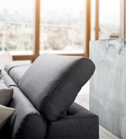 Graues Sofa mit verstellbarer Kopfstütze, seitliche Perspektive in einem modernen Wohnzimmer.
