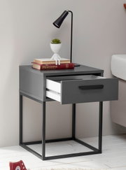Moderne Nachtkommode mit offenem Schubfach, dekoriert mit Büchern, einer Pflanze und einer Lampe, seitliche Perspektive