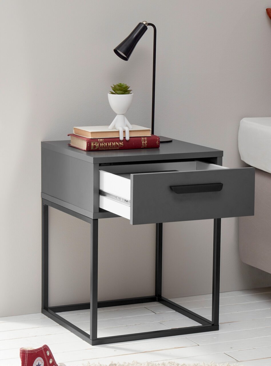 Moderne Nachtkommode mit offenem Schubfach, dekoriert mit Büchern, einer Pflanze und einer Lampe, seitliche Perspektive